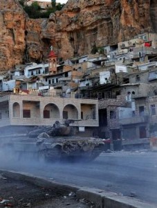 FILE/ASSOCIATED PRESS A Syria government tank moves through the village of Maaloula northeast of Damascus. Christians have fled battle zones by the thousands as Islamist rebels fight to overthrow the Syrian leadership.