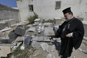 (AP Photo/Lefteris Pitarakis) Greek Orthodox Archbishop of Gaza Alexios, shows destroyed graves, hit by an Israeli strike, at the cemetery of the St. Porphyrios church, in Gaza City, on Sunday, Aug. 10.