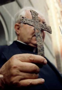 Fr John Romas holding a cross found in the ruins of St Nicholas Church.